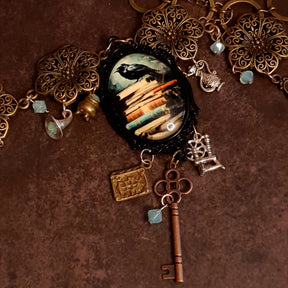 Side angle of black crow fairy tale necklace with witchy charms and Swarovski crystals, Fairy tale book charm Spinning wheel Ornate skeleton key,  Victorian style vintage style jewelry by Rachel Flam Design
