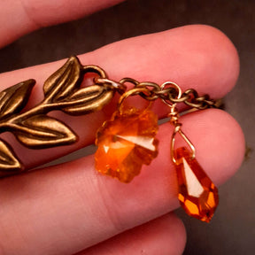 swarovski crystal necklace with large yellow icicle crystal and flower crystals in green and orange. Autumn necklace with nature motifs pinecone leaves and 2 intertwined snakes