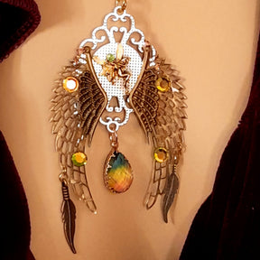 victorian style necklace with a peacock cabochon. Bright golden yellow and green crystals. Feather accents, a fairy, and a striking teardrop crystal
