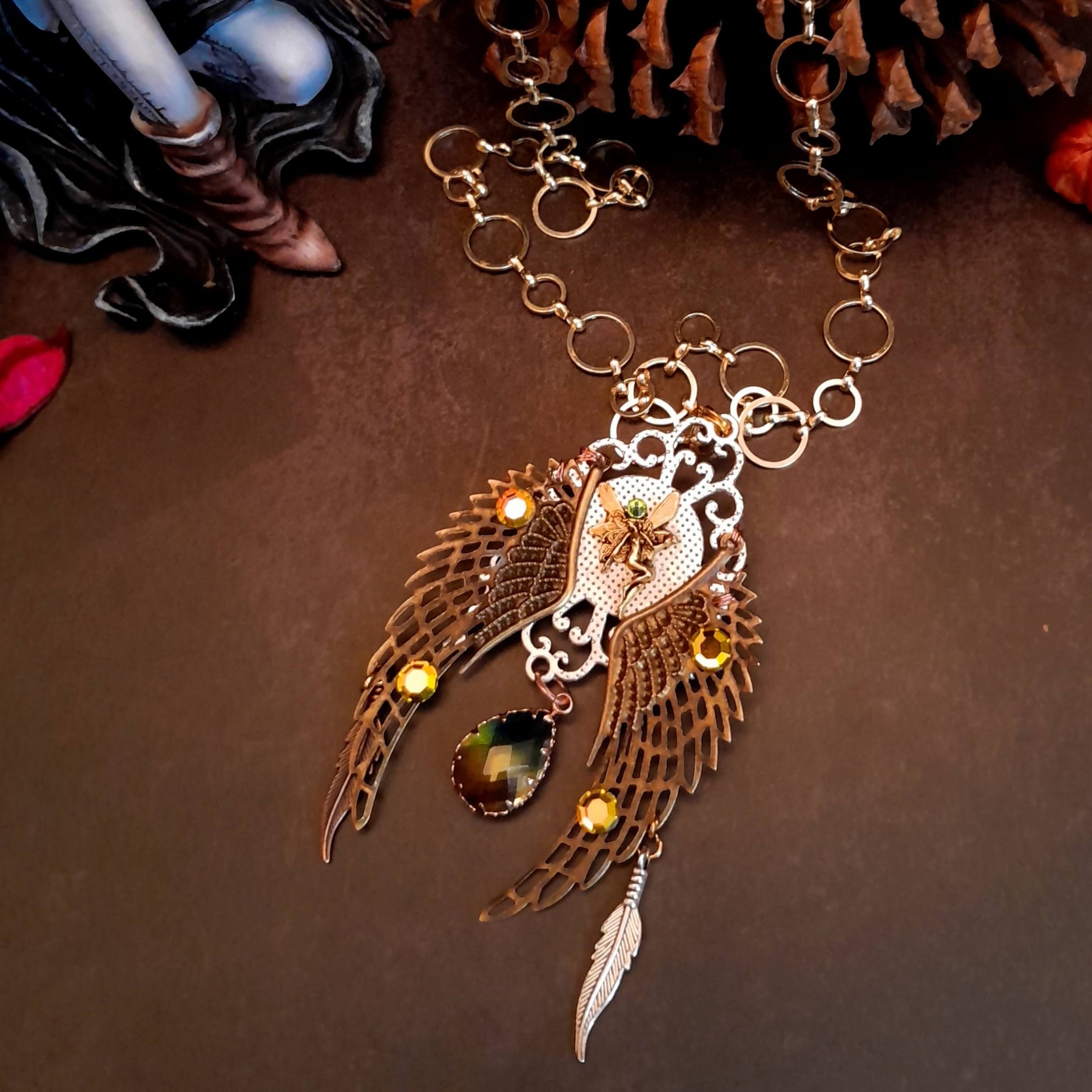 victorian style necklace with a peacock cabochon. Bright golden yellow and green crystals. Feather accents, a fairy, and a striking teardrop crystal