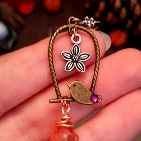 bird earrings with dangling flower and glass drops that change color from yellow to pink. wire wrapped with a moon and star