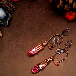 bird earrings with dangling flower and glass drops that change color from yellow to pink. wire wrapped with a moon and star