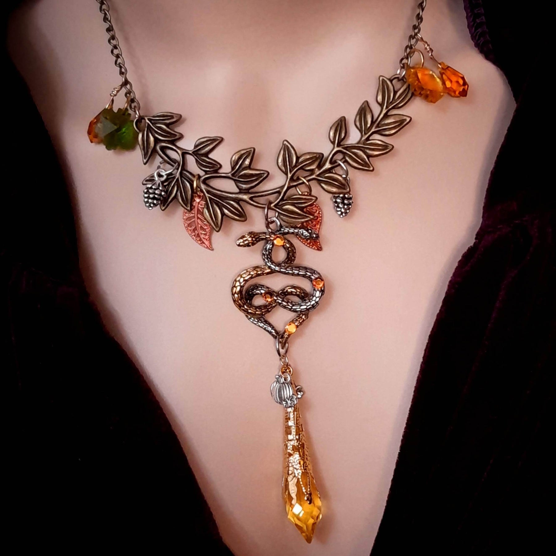 swarovski crystal necklace with large yellow icicle crystal and flower crystals in green and orange. Autumn necklace with nature motifs pinecone leaves and 2 intertwined snakes