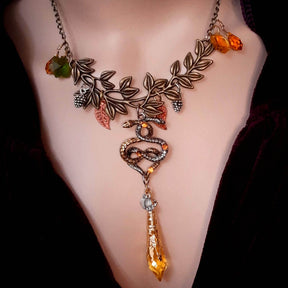 swarovski crystal necklace with large yellow icicle crystal and flower crystals in green and orange. Autumn necklace with nature motifs pinecone leaves and 2 intertwined snakes