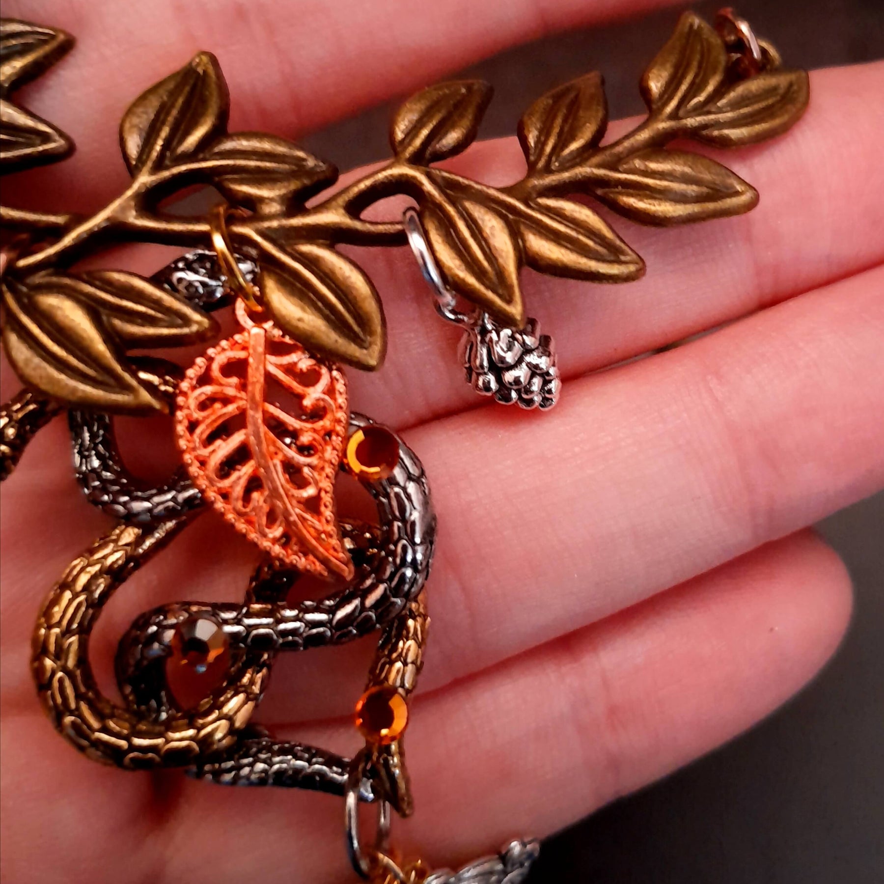 swarovski crystal necklace with large yellow icicle crystal and flower crystals in green and orange. Autumn necklace with nature motifs pinecone leaves and 2 intertwined snakes