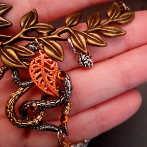 swarovski crystal necklace with large yellow icicle crystal and flower crystals in green and orange. Autumn necklace with nature motifs pinecone leaves and 2 intertwined snakes