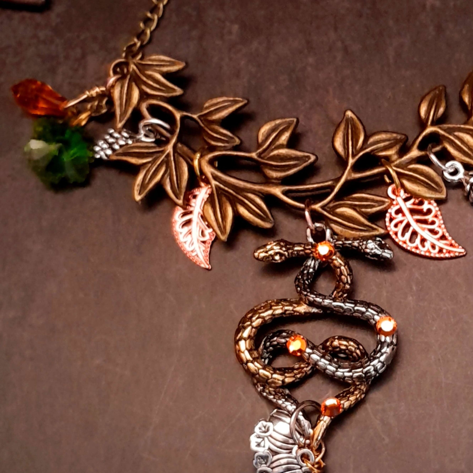 swarovski crystal necklace with large yellow icicle crystal and flower crystals in green and orange. Autumn necklace with nature motifs pinecone leaves and 2 intertwined snakes