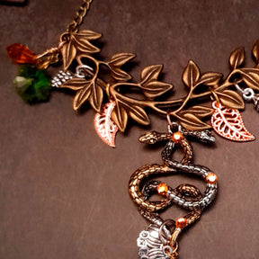 swarovski crystal necklace with large yellow icicle crystal and flower crystals in green and orange. Autumn necklace with nature motifs pinecone leaves and 2 intertwined snakes