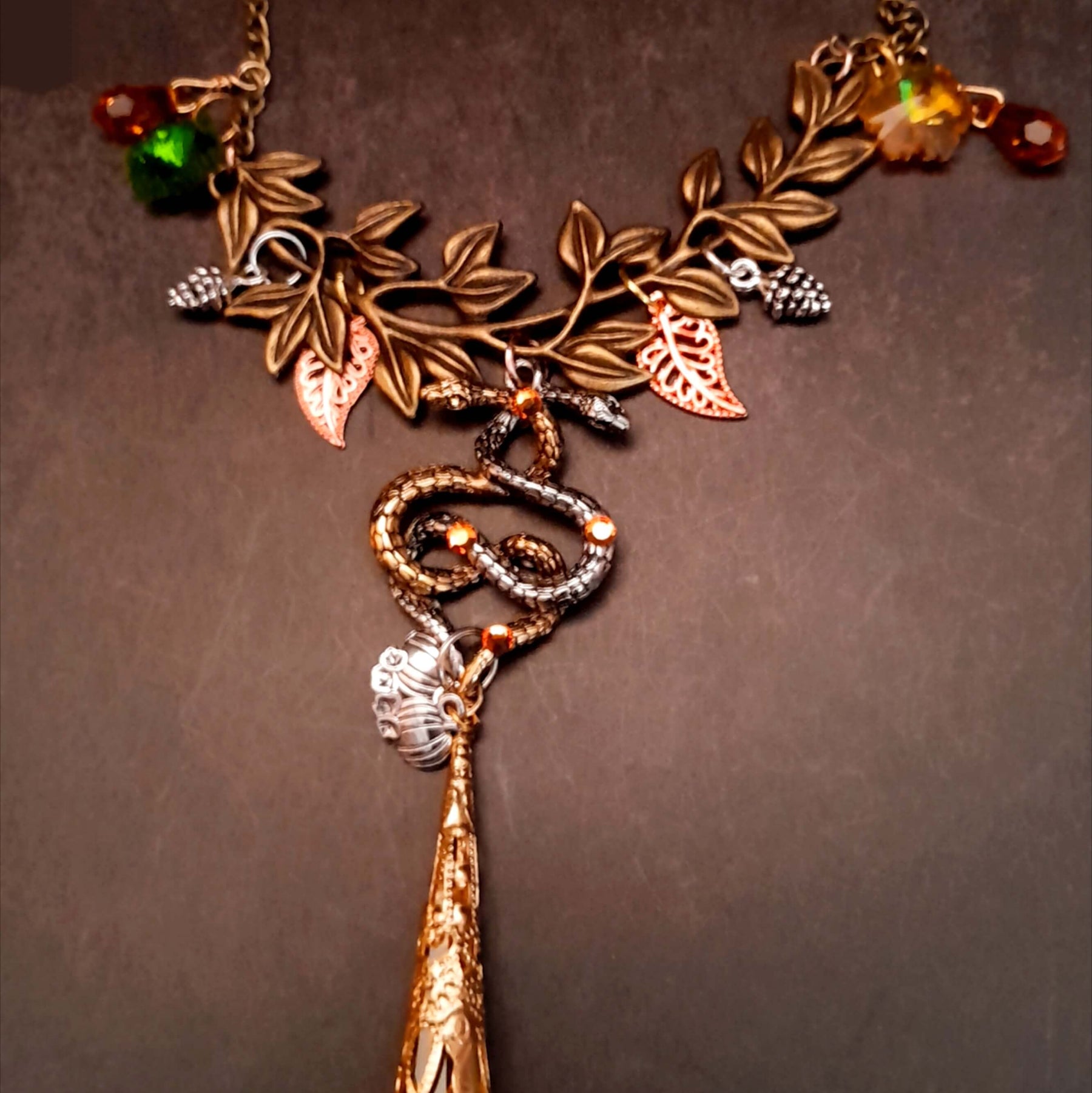 swarovski crystal necklace with large yellow icicle crystal and flower crystals in green and orange. Autumn necklace with nature motifs pinecone leaves and 2 intertwined snakes
