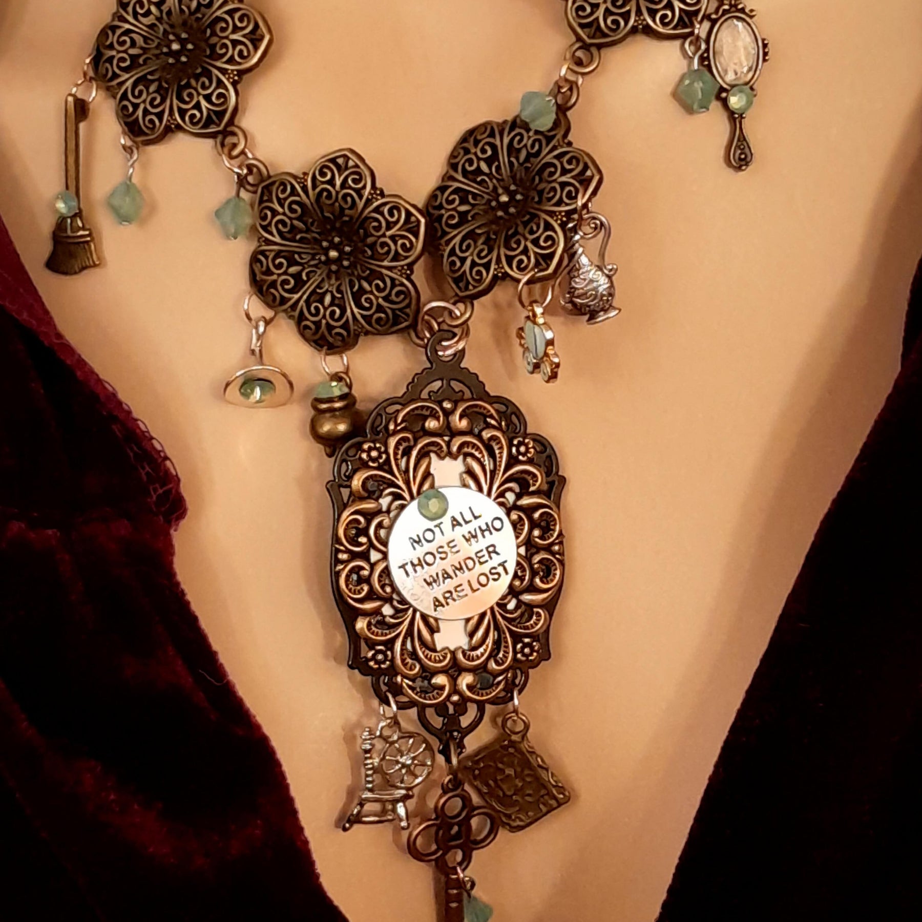Back of crow necklace showing Not All Those Who Wander Are Lost quote in filigree with a Swarovski crystal accent, Victorian style vintage style jewelry, Rachel Flam Design