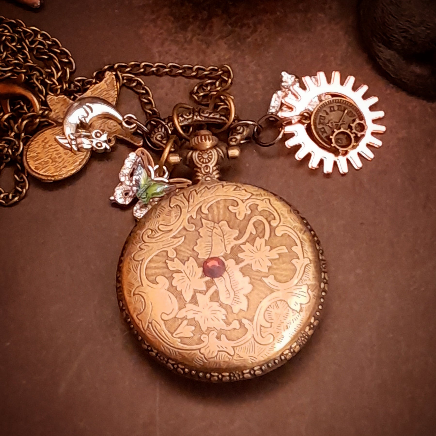 Back of magical steampunk pocket watch necklace with engraved botanical scrollwork and Swarovski crystal accent, handmade Victorian style jewelry