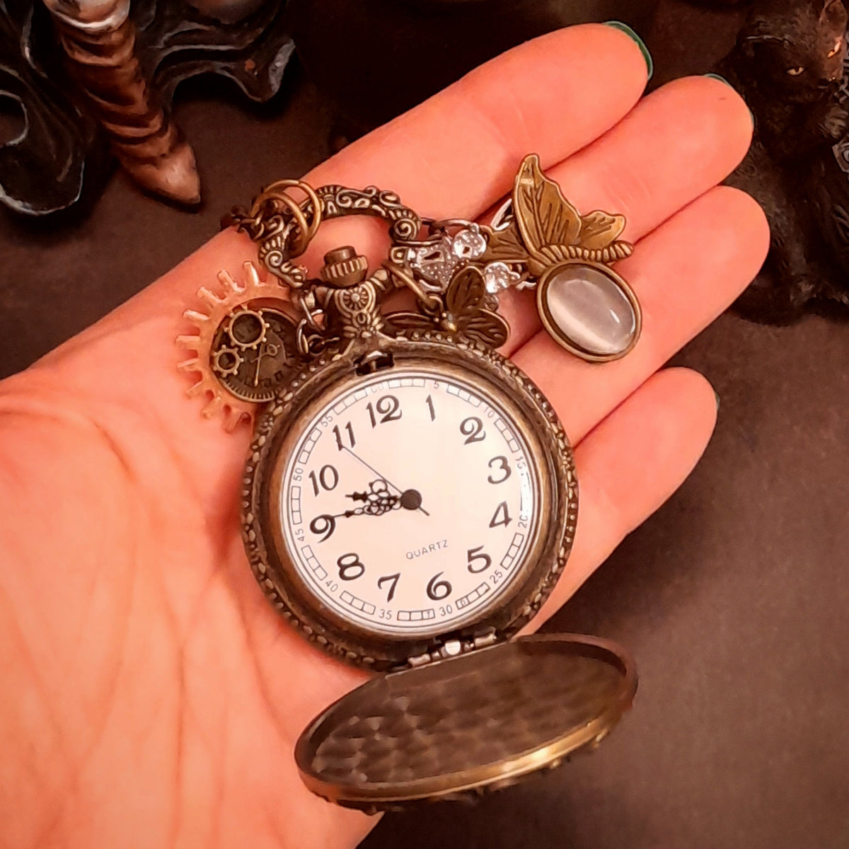 Close up of handmade steampunk pocket watch necklace featuring vintage style gears, lavender purple Austrian crystals and butterfly details