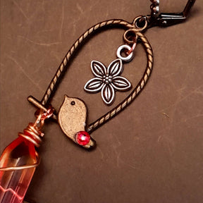 bird earrings with dangling flower and glass drops that change color from yellow to pink. wire wrapped with a moon and star
