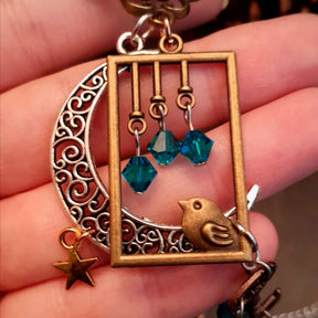 Victorian style bird necklace with tree of life cabochon, bird cage and bird, turquoise swarovski crystals silver filigree moon gold star and copper leaf. 