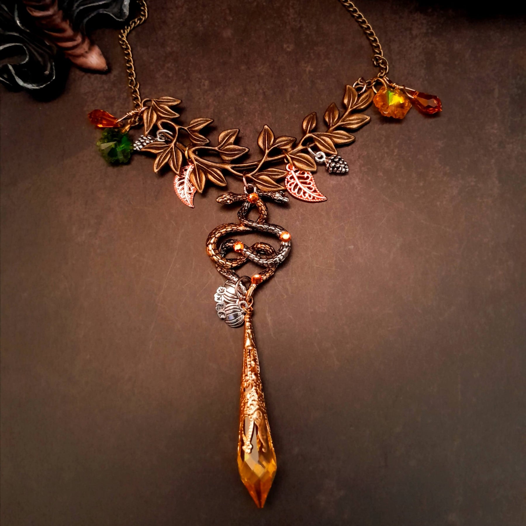 swarovski crystal necklace with large yellow icicle crystal and flower crystals in green and orange. Autumn necklace with nature motifs pinecone leaves and 2 intertwined snakes